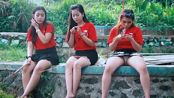 Seorang gadis muda memberikan teman-temannya mengintip di bawah roknya memancing